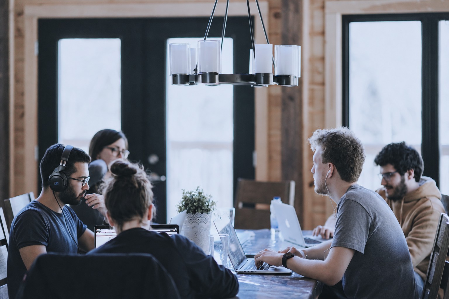 People sitting around a table together, working on laptops
