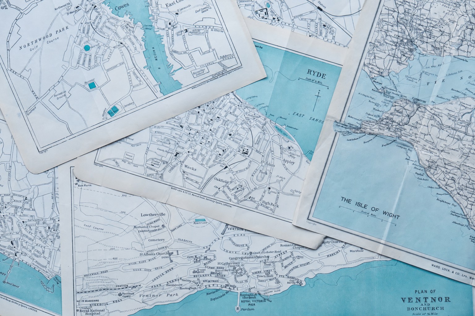 A collage of overlapping printed maps, viewed from above